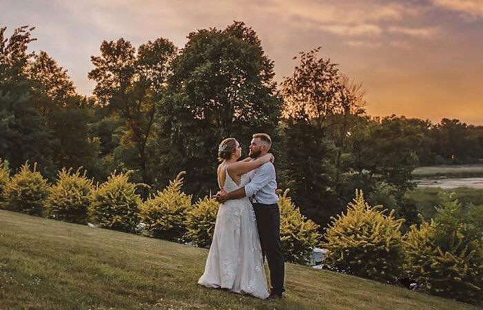 A wedding couple sharing a moment while the sun is setting, surrounding by a hilly vista