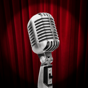 A vintage microphone with a maroon curtain backdrop.