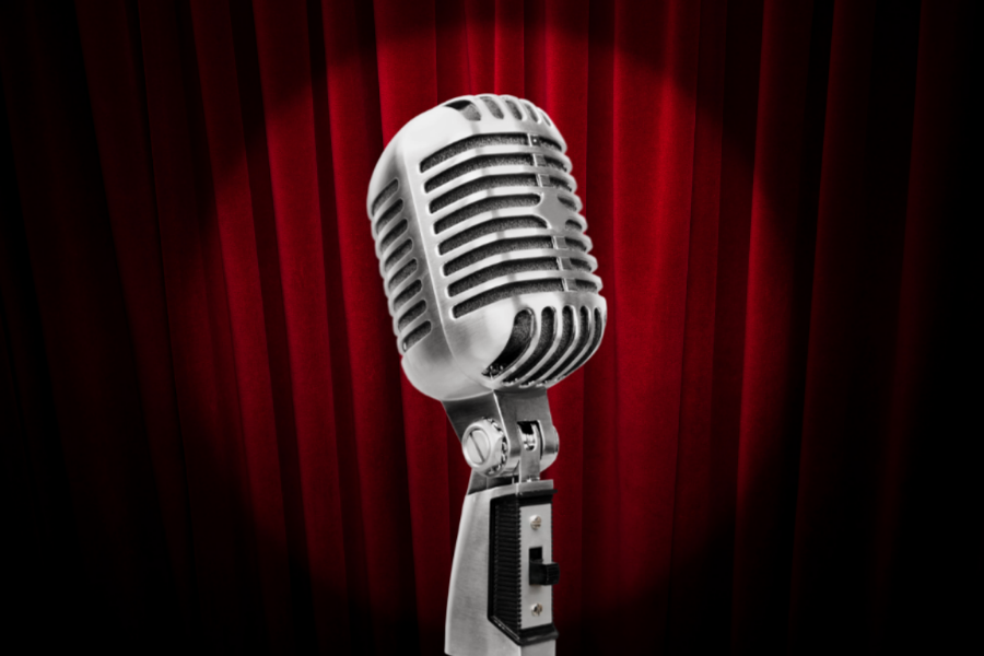 A vintage microphone with a maroon curtain backdrop.
