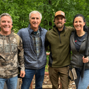 A group of friends at a shooting event, a nice day outside.
