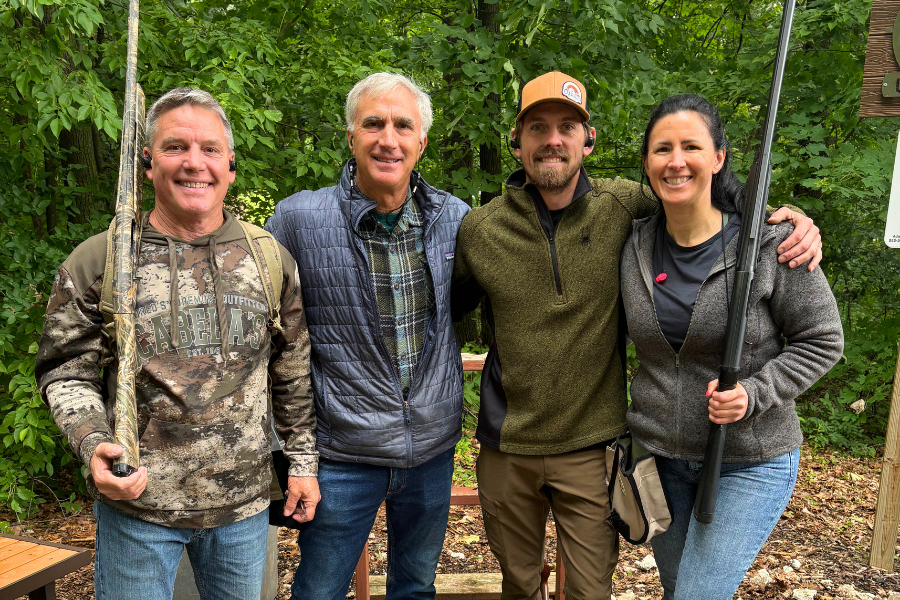 A group of friends at a shooting event, a nice day outside.