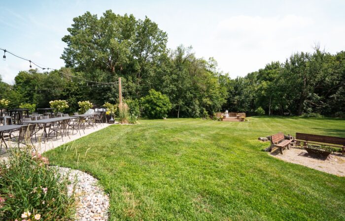 green lawn with fire pit on side and tables and chairs on patio.