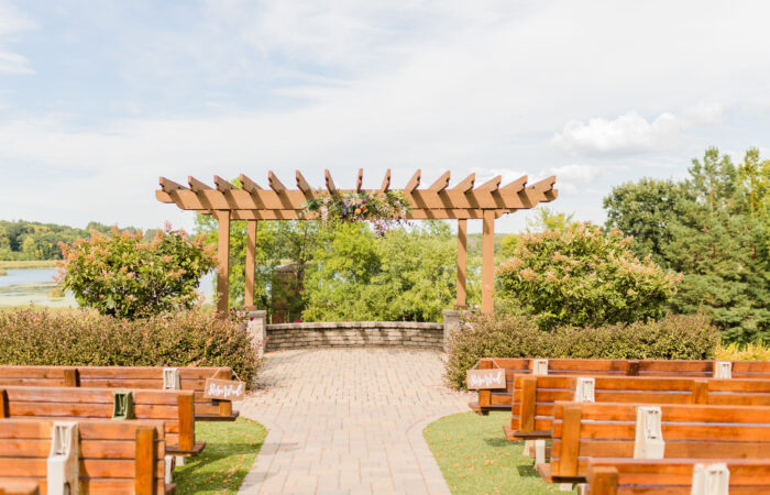 Arbor with flowers on top center. Brick pathway and on ground below arbor.