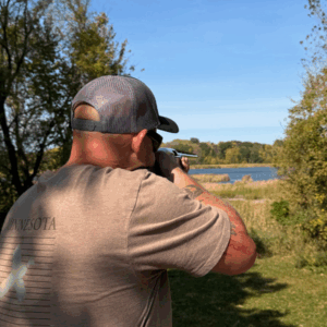 Man taking aim with a shotgun at a clay target