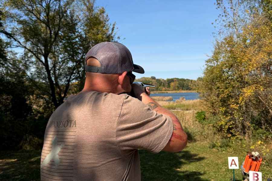 Man taking aim with a shotgun at a clay target