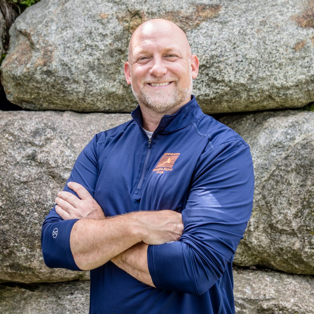 man in blue shirt with arms crossed smiling